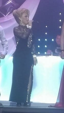 Cucusa Minelli cantando en un escenario con vestido negro