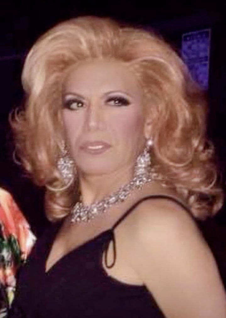 Retrato de Cucusa Minelli con peluca rubia y vestido negro