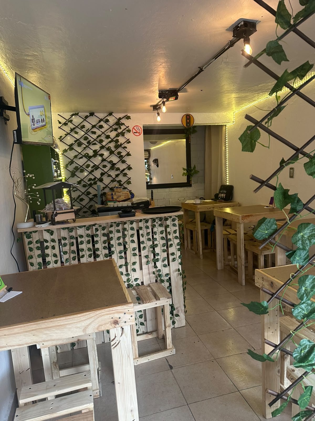 Mesas de madera, luces cálidas y decoración vegetal dentro de El Semáforo Café