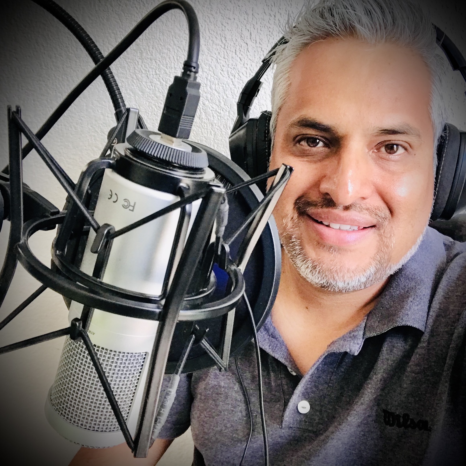 Conductor usando audífonos junto al micrófono del podcast